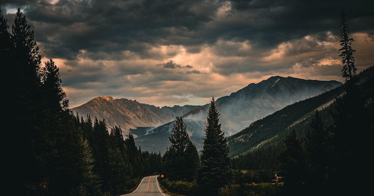 Route dégagée traversant des montagnes sombres sous un ciel dramatique